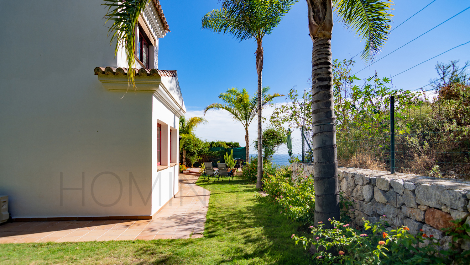 Une mignonne villa entourée de jardins avec vue latérale sur la mer
