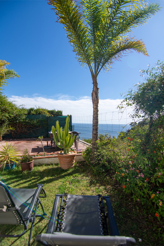 Une mignonne villa entourée de jardins avec vue latérale sur la mer