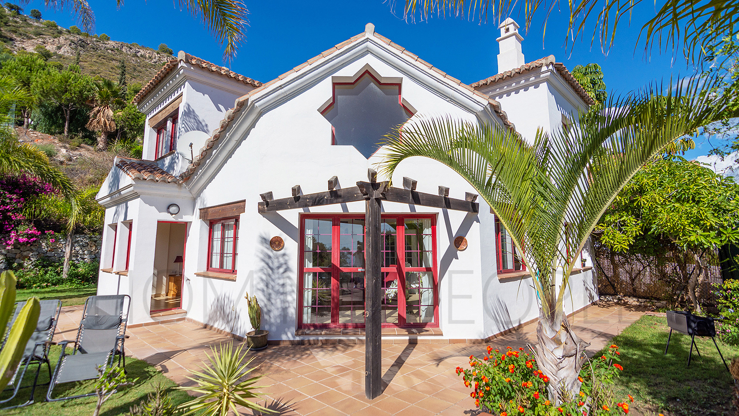 Une mignonne villa entourée de jardins avec vue latérale sur la mer
