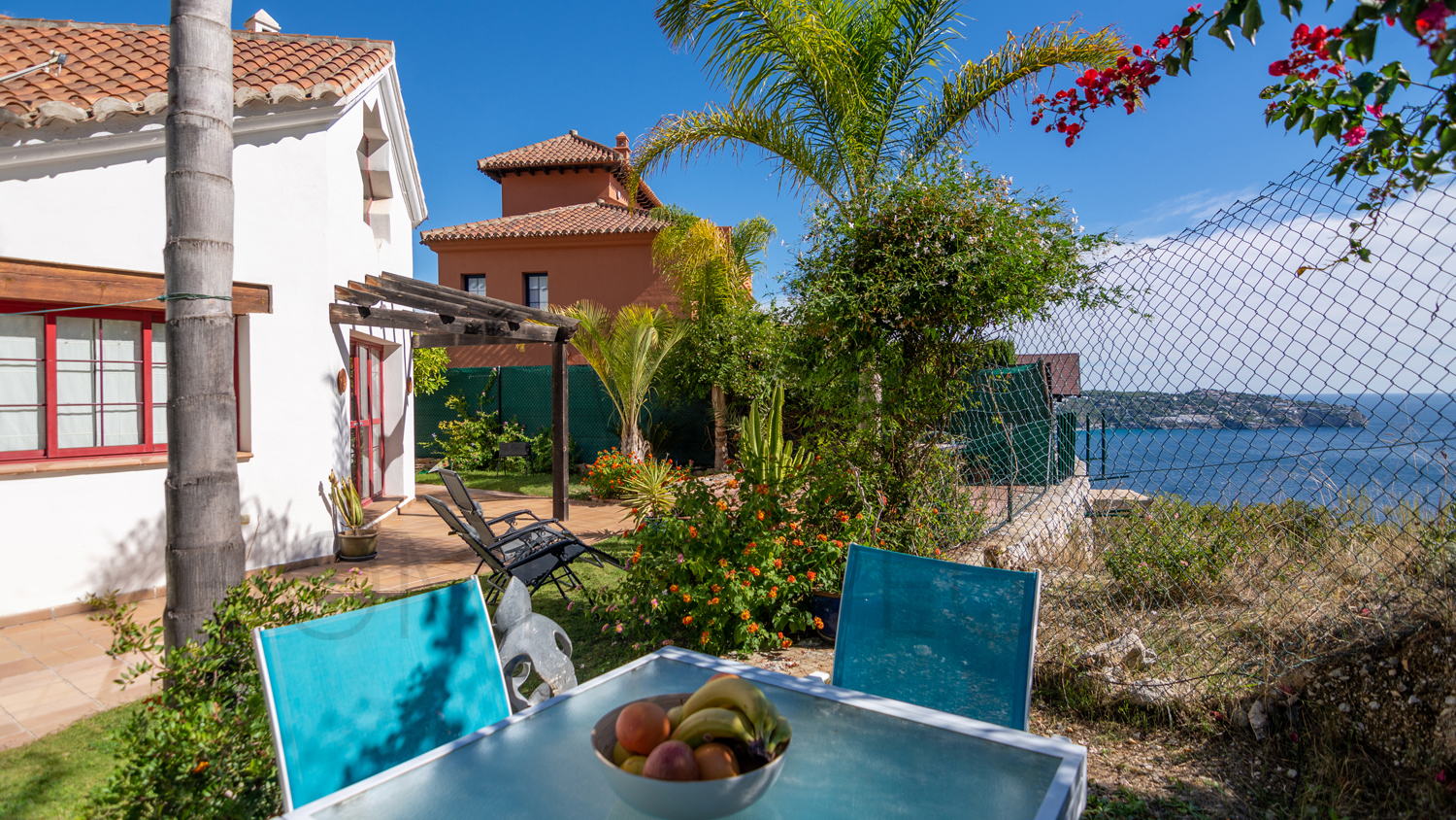 Une mignonne villa entourée de jardins avec vue latérale sur la mer
